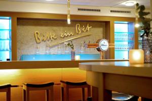 a restaurant with a bar with chairs and a clock at Zum Simonbräu in Bitburg +1 photo