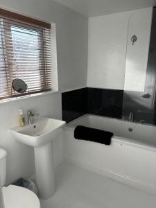 a white bathroom with a sink and a bath tub at Nanny and Chips House in Whitby