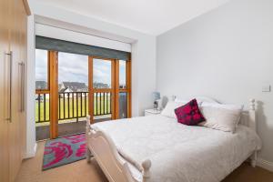 a white bedroom with a bed and a balcony at Shannonside - Stylish 5 Bed Marina home & 40ft mooring in Termonbarry