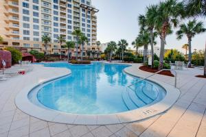 a swimming pool at a resort with palm trees and buildings at Luau II 7021 Studio in Destin