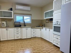 a large kitchen with white cabinets and a window at וילת אבן ספיר in Gefen