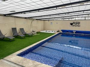 a large swimming pool with chairs and grass in a room at וילת אבן ספיר in Gefen