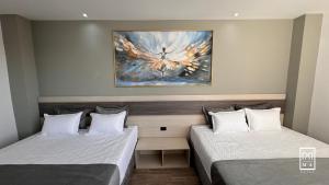 twee bedden in een kamer met een schilderij aan de muur bij M A Hotel in Popayan