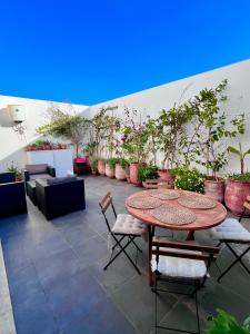 um pátio com uma mesa, cadeiras e vasos de plantas em Welcome to your happy place ! em Dar Bouazza