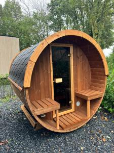 een groot rond houten gebouw met banken erin bij Kindvriendelijk luxe chalet in de bossen met privé sauna in Harderwijk