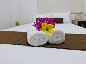 a pair of towels with a flower on a bed at JetPoint Holiday Home in Nadi