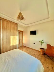 ein Schlafzimmer mit einem Bett, einem Stuhl und einer Pflanze in der Unterkunft Welcome to your happy place ! in Dar Bouazza