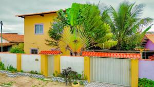a yellow house with a palm tree behind a fence at Lar Lalunalê 3 in Prado