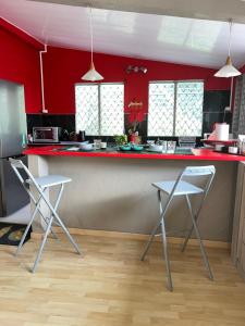 une cuisine avec un comptoir rouge et deux tabourets dans l'établissement LOCATION SAISONNIÈRE DE 154 M2, au François