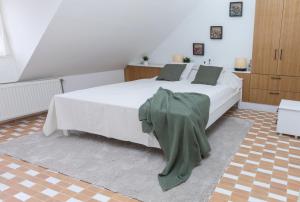 PécselyにあるPécsely House Apartmanのベッドルーム1室(白いベッド1台、緑の毛布付)