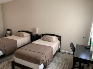 1 dormitorio con 2 camas, mesa y escritorio en Sebastian Gardens Inn & Suites, en Sebastian