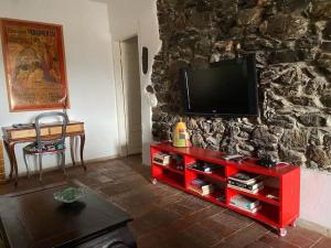 a red entertainment center with a television on a stone wall at Vezzhouse in Vezzano Ligure