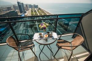 a table and chairs on a balcony with a view of the ocean at Apartments Beach Tower in Batumi