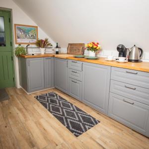 a kitchen with gray cabinets and a wooden floor at Cwtch Lackerlee in Haverfordwest