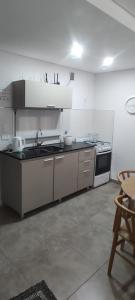 a white kitchen with a stove and a sink at Departamento por día Junín Centro in Junín +2 photos