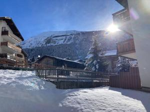 a snow covered yard with a fence and a mountain at Gemütliches Bergidyll mit top Lage in Leukerbad