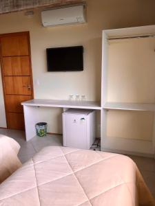 ein Schlafzimmer mit einem Bett und einem TV an der Wand in der Unterkunft Pousada In Garden in Teresópolis