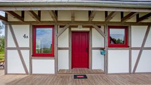 a red door and three windows on a building at Domek Pogodny Rowy Szachulcowa 4a in Rowy