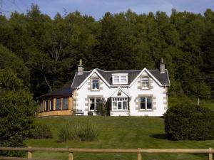 ein großes weißes Haus auf einem Hügel in der Unterkunft Ness Castle Lodges in Inverness