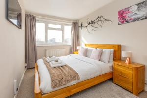 a bedroom with a large bed with a wooden frame at 2BR wbalcony, Battersea, 5min Clapham Junction St in London