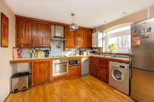 a kitchen with wooden cabinets and a stainless steel refrigerator at 2BR wbalcony, Battersea, 5min Clapham Junction St in London