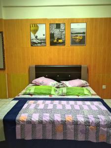 Una cama con almohadas rosas y verdes en un dormitorio en PD Corus myHoliday Homes & Apartments, en Port Dickson