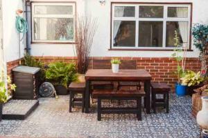 patio con tavolo in legno e alcune piante di Charming studio suite minimum 2 night stay a Southwick