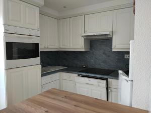 a white kitchen with white cabinets and a wooden counter top at Farniente in Camiers