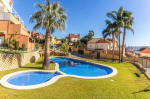 - une piscine dans une cour avec des palmiers dans l'établissement Costa Verde, à Finestrat