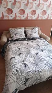 a bed with a black and white comforter at Terre de Bourgogne - Appartement au centre ville d'Avallon in Avallon