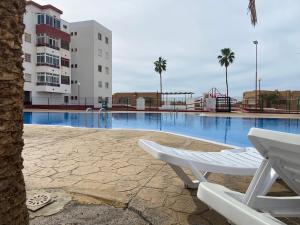 a swimming pool with a white chair next to a building at Apartamento de 3 hab en Costa Adeje centro in Adeje