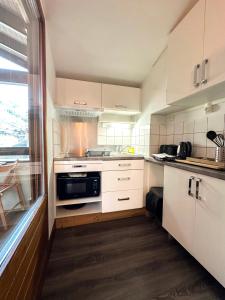 una cocina con armarios blancos y horno negro en 2- Studio Brides-les-bains tout confort avec vue Vanoise, en Brides-les-Bains