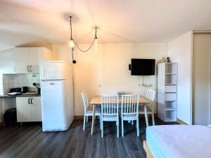 a kitchen and a table with chairs and a refrigerator at 2- Studio Brides-les-bains tout confort avec vue Vanoise in Brides-les-Bains