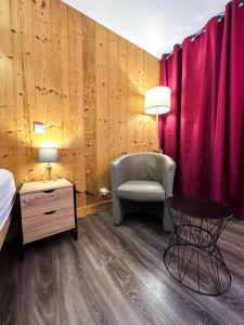 una camera da letto con tende rosse, una sedia e un tavolo di 2- Studio Brides-les-bains tout confort avec vue Vanoise a Brides-les-Bains