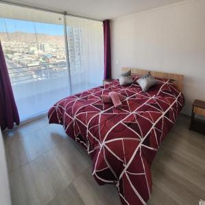 a bed in a bedroom with a large window at Departamento ejecutivo in Antofagasta