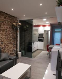 a living room with a stone wall and a kitchen at Apartamento en San Sebastián con patio exterior in Añorga-Lugariz