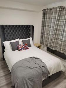 a bedroom with a large bed with a black headboard at Newly Renovated Cosy 1 bed flat, 4 minutes walk to Town Centre, 3 minutes walk to the train station, Free parking, Modern, fresh and spacious living room, Netflix ready smart TV, Wifi in Wellingborough