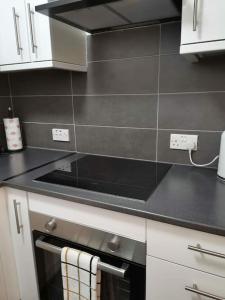 a kitchen with a stove top oven in a kitchen at Newly Renovated Cosy 1 bed flat, 4 minutes walk to Town Centre, 3 minutes walk to the train station, Free parking, Modern, fresh and spacious living room, Netflix ready smart TV, Wifi in Wellingborough