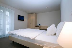 a bedroom with a white bed with white pillows at Hotel Ochsen in Uster