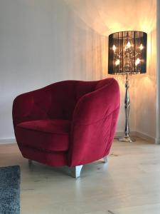 un fauteuil rouge dans un salon avec une lampe dans l'établissement Harmony&Apollo, à Adenau