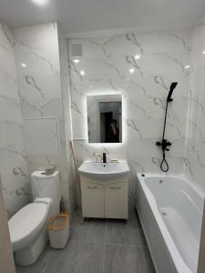ein Badezimmer mit einem Waschbecken, einer Badewanne und einem WC in der Unterkunft квартира in Aqtau