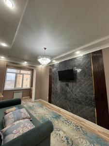 ein Wohnzimmer mit einem grünen Sofa und einem TV in der Unterkunft квартира in Aqtau