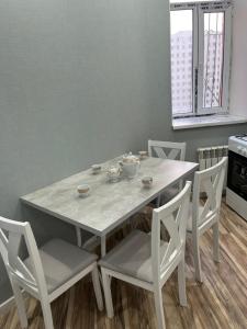 einen weißen Tisch und Stühle mit Tassen und Schüsseln darauf in der Unterkunft квартира in Aqtau