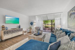 Una sala de estar con un sofá azul y una mesa. en Beachwalk Villa 5125, en Destin