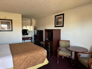 Habitación de hotel con cama, escritorio y mesa. en Royal Inn en Albany
