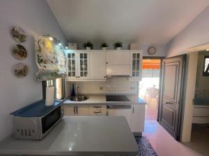 a kitchen with white cabinets and a microwave at Santa Fe Bunglow Deluxe Playa Del Ingles in Maspalomas
