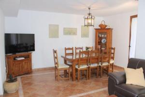 uma sala de jantar com mesa e cadeiras e uma televisão em ACOGEDOR ADOSADO DE ESQUINA. LAS LOMAS. JUNTO AL ALGARVE PORTUGUÉS. em Huelva