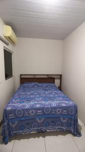 um quarto com uma cama com um edredão azul em Cozy em Palmas