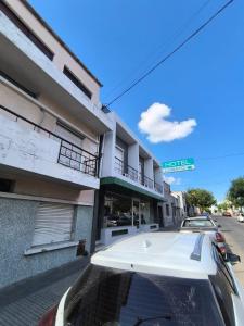 un coche blanco estacionado frente a un edificio en Hotel Lobato, en Paysandú