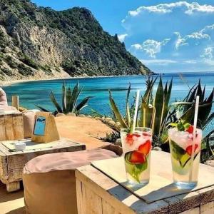 two drinks on a table with a view of the ocean at Private Family Size Villa in Nature with Tennis, Basketball and Football Courts for Holidays and Retreats in Sant Rafael de Sa Creu